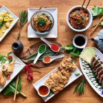 High angle view of traditional Japanese food dishes served on the table. Set of sushi, rolls, spaghetti pasta, edamame and tuna tataki.