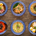 Set of different types of Japanese ramen, tantanmen, shio ramen, shrimp, wood mushrooms, top view on a wooden background, in blue traditional bowls